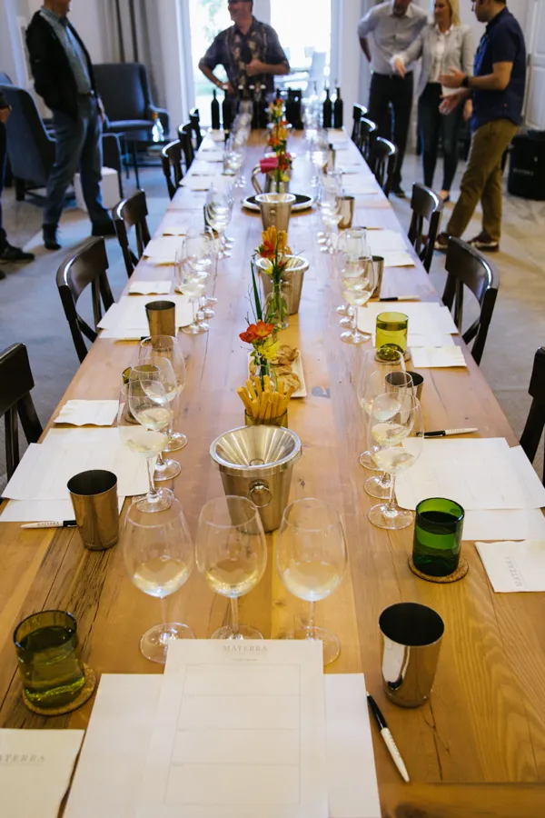 Long table set with wine glasses, bottles, and flowers for event