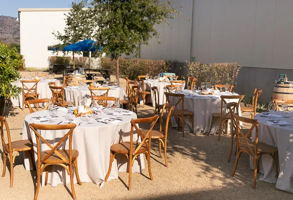 Outdoor dining tables with white tablecloths set in vineyard