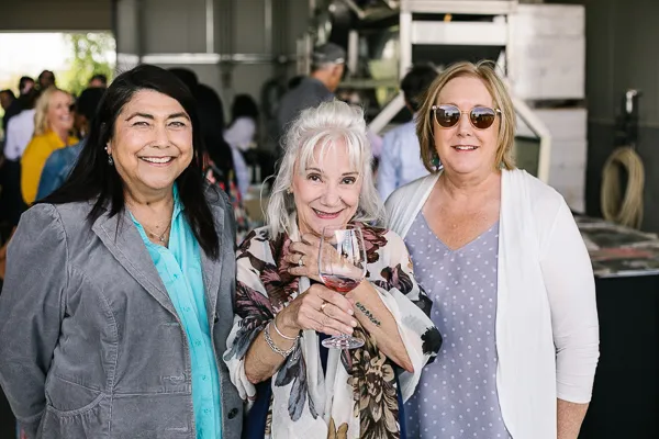 Three women toasting with wine glasses at indoor winery event