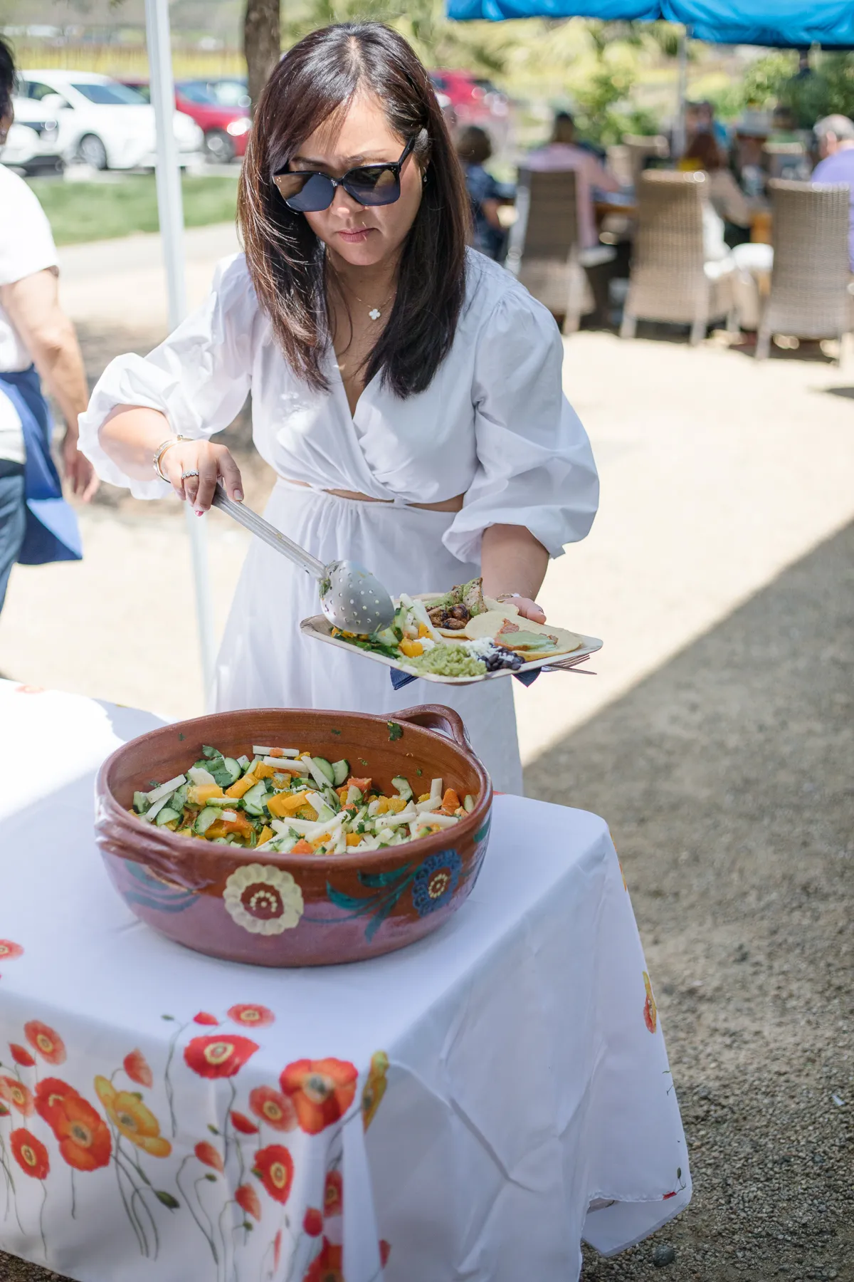 Woman serving salad from decorative bowl at outdoor winery event