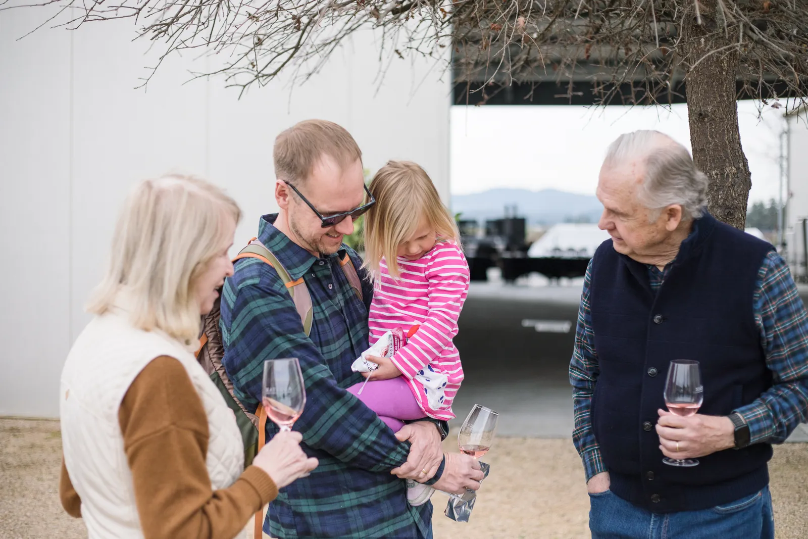 Family of four with wine glasses at lakeside white building