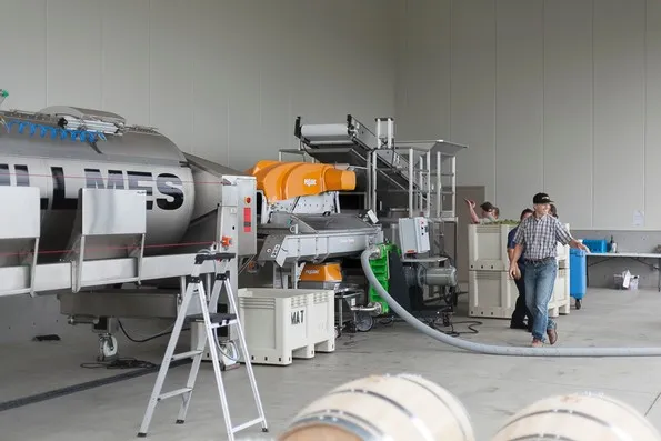 Worker monitoring large-scale harvest processing with crusher equipment