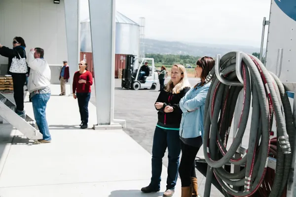 Winery staff at bottling facility with processing hoses and equipment