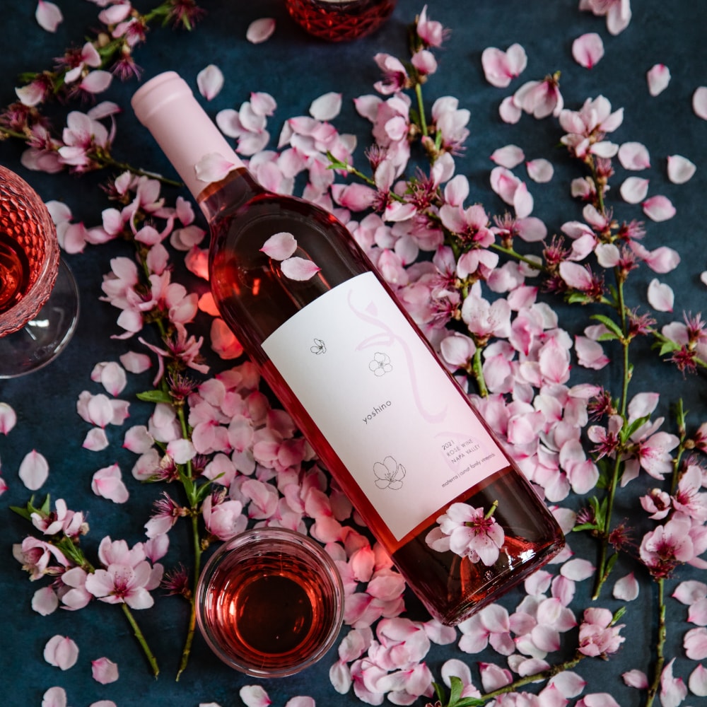 A bottle of rosé wine laid flat on a bed of pink cherry blossom petals